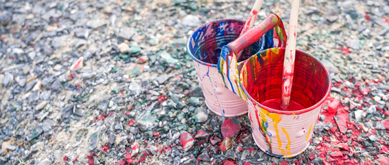 Buckets of colors on ground, Paint cans with paintbrushes, Blue and red colors in the pots