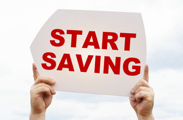 Against the background of the sky in the hands of a man is a sign with the inscription - Start Saving