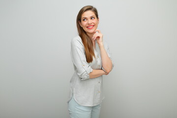 Thinking woman looking up isolated portrait, young lady dressed pants and gray shirt.