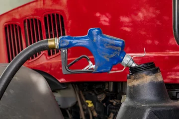 Schilderijen op glas Diesel fuel nozzle fueling farm tractor. Farming input costs, fuel price increase and emissions pollution concept. © JJ Gouin