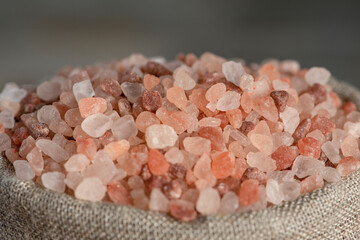 Fototapeta na wymiar Salt price. Large crystals of pink Himalayan salt, close-up. A coin in a pile of salt as a symbol of rising prices.