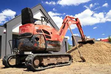 A mini excavator prepared to spread the aggregate on the construction site.
Minikoparka...