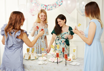 A group of a happy wome celebrating together during the genre reveal the party, over balloons and confetti background.