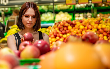 Fototapeta na wymiar Woman in a supermarket at the shelf for fruits shopping apple