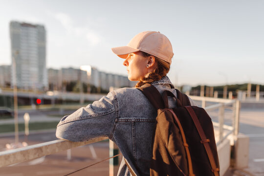 Tourist girl with her backpack at sunset looking at city landscape, back view Adventure and travel in the concept . Backpack rear view. Tourism in city.
