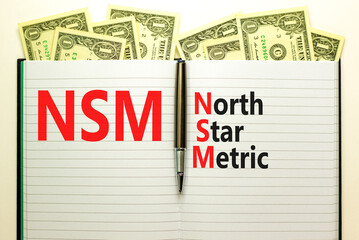 NSM north star metric symbol. Concept words NSM north star metric on white note on a beautiful white background. Dollar bills. Metallic pen. Business and NSM north star metric concept. Copy space.