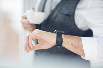Obraz na płótnie Canvas Close-up of unrecognizable businessman drinking coffee and using smart watch to see notifications