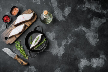 Piece of fresh raw halibut fish, with ingredients and rosemary herbs, on black dark stone table...