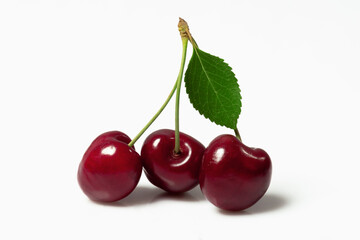 Ripe cherry on a branch with a leaf on a white background.