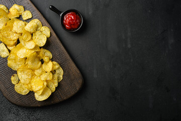Chesapeake Bay Crab Spice Flavored Potato Chips on black dark stone table background, top view flat...