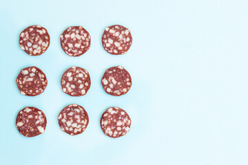 Top and side views of smoked salami sausage slices isolated on blue background