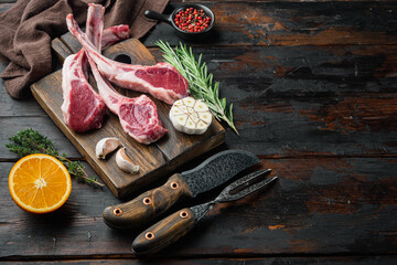 Fresh raw butchers lamb beef cutlets, with ingredients carrot orange, herbs, on old dark  wooden table background , with copyspace  and space for text