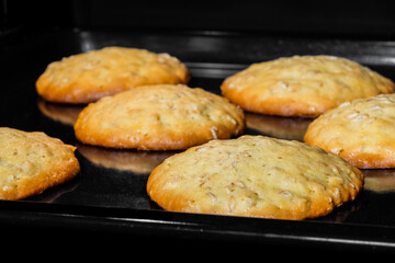 Close up view: many baked homemade crunchy oatmeal cookies on metal sheet in oven. Dessert, cookery, baking, gastronomy concept
