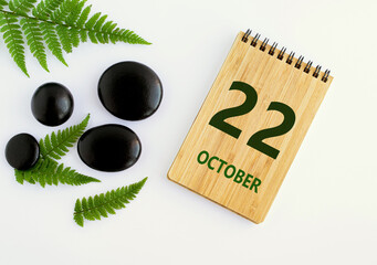 October 22. 22th day of the month, calendar date. Notepad, black SPA stones, green leaves. Autumn month, day of the year concep