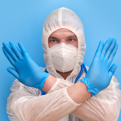 Man doctor medic in a protective suit uniform with goggles and face mask on a studio blue background. Paramedic in white antiviral protective clothing wearing an N95 respirator and safety glasses