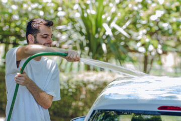 young man washing the car with a hose