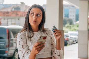 latin girl in the street with mobile phone and credit card