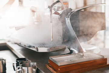 Coffee machine in steam, barista preparing coffee at cafe