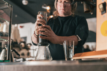 Professional Barista press to device and coffee drops pours trought aeropress to pot