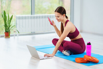 a sports woman with laptop sends a message to students for an online workout