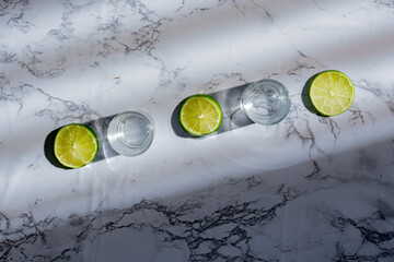 Vasos tequileros y rodajas de limón con fondo de mármol