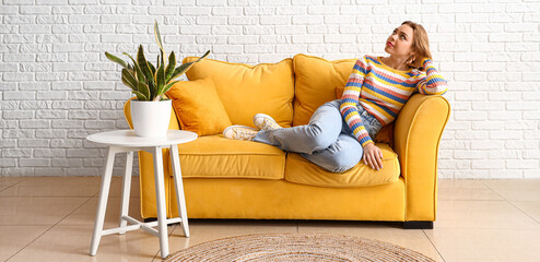 Beautiful young woman relaxing on sofa at home