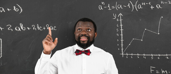 African-American maths teacher near blackboard in classroom