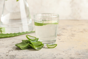 Glass of aloe juice with leaves on grunge background, closeup
