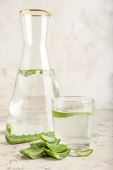 Glasses of aloe juice with leaves on grunge background