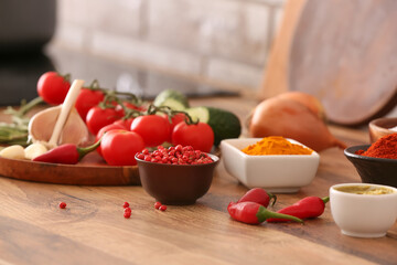 Bowls with different spices and fresh vegetables on table in kitchen