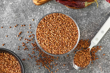 Bowl and spoon with buckwheat grains on grunge table