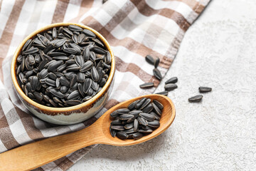 Bowl, spoon and napkin with black sunflower seeds on white background