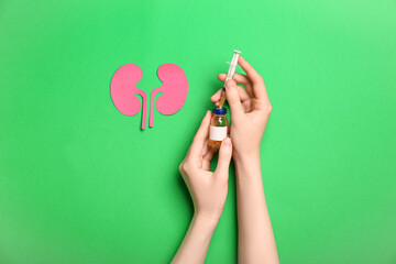 Woman with ampule, syringe and paper kidneys on green background