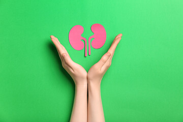 Woman with paper kidneys on green background