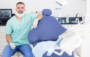 Portrait of positive professional male dentist at his workplace in dental clinic