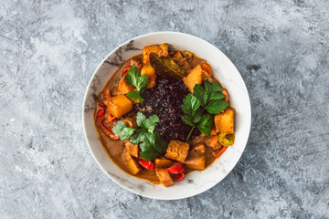 healthy plant-based food, vegan potato tempeh and bell peppers curry with black rice and fresh coriander