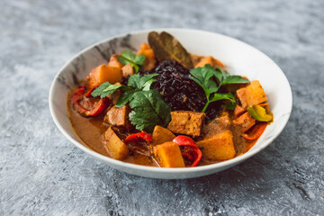 healthy plant-based food, vegan potato tempeh and bell peppers curry with black rice and fresh coriander