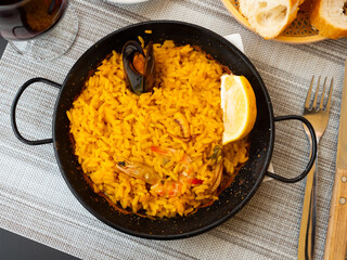 Traditional paella marinera with shrimps and mussels served on iron frypan