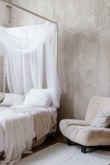 Armchair standing near boho bed with cushions, pillows and bedding
