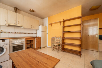 Image of kitchen front with cherry cabinets below and light cabinets above with white built-in appliances, yellow painted walls and tile, and a solid wood side table and shelving