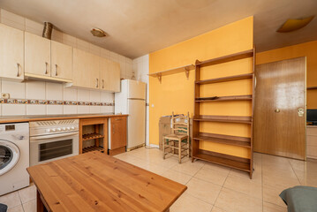 Image of kitchen front with cherry cabinets below and light cabinets above with white built-in appliances, yellow painted walls and tile, and a solid wood side table and shelving
