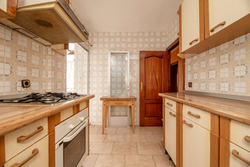 Fototapeta premium Kitchen with old wooden furniture on both sides of the wall and kitsch vintage cream tiles and stoneware floors, wooden table and reddish carpentry