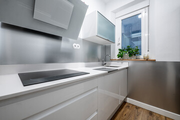 Kitchen corner with plain white cabinets, lots of anodized aluminum, and built-in appliances