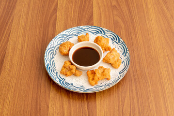 Plate of small tori katsu chicken bites with dipping sauce on white and blue plate
