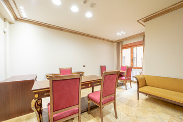 Professional office with vintage hardwood furniture with red fabric chairs and yellow fabric divan