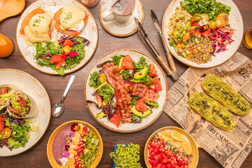Fototapeta na wymiar Set of healthy breakfast and brunch dishes with eggs benedict, acai bowl, fried bacon, avocado with pumpkin seeds and vegetables