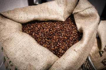 Zelfklevend Fotobehang an open jute bag with roasted coffee beans © gehapromo