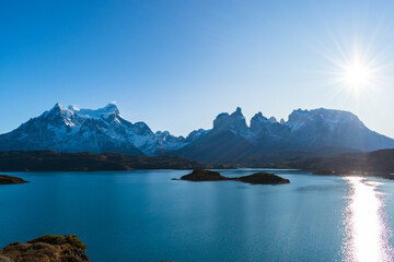cuernos del Paine , octava maravilla del mundo, montañas, con cielo despejado azul con sol radiante,  lago azul con islas