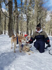 Woman playing with dog on snow sled