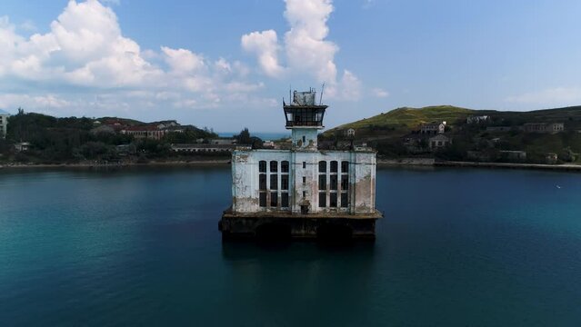 A big white fortress in the sea. Shot.A large white building controlling the raging sea next to bridges and mountains.